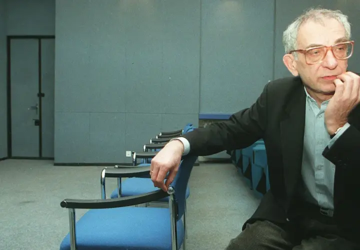 Krzysztof Kieślowski, reżyser znany z głębokich filmów, siedzi w pustej sali.