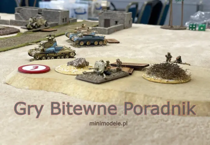 Miniaturowe czołgi i żołnierze na pustynnym polu bitwy. Sceneria do figurkowych gier bitewnych.