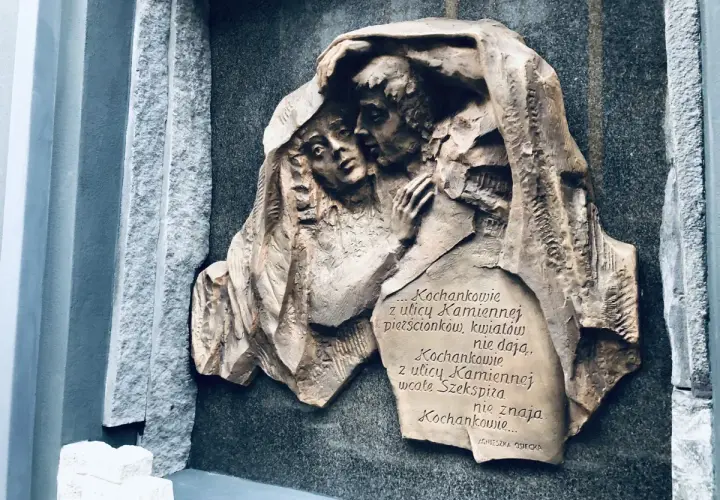 Rzeźba na kamiennej płycie przedstawia przytulonych kochanków. Cytat z Agnieszki Osieckiej mówi o miłości z ulicy Kamiennej.