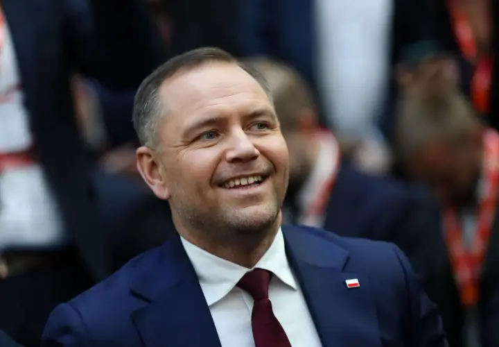 Uśmiechnięty mężczyzna w garniturze z polską flagą na klapie. Czy to jego styl życia wyjaśnia, dlaczego urząd prezydenta jest uznawany za najdroższy w utrzymaniu w całej Europie Środkowej?