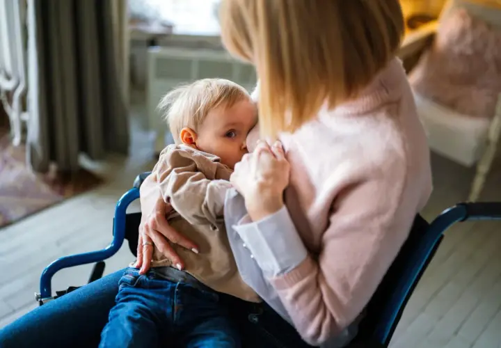 Mama w wózku karmi piersią dziecko. Decyzja o rezygnacji z karmienia piersią może być trudna, ale miłość pozostaje.