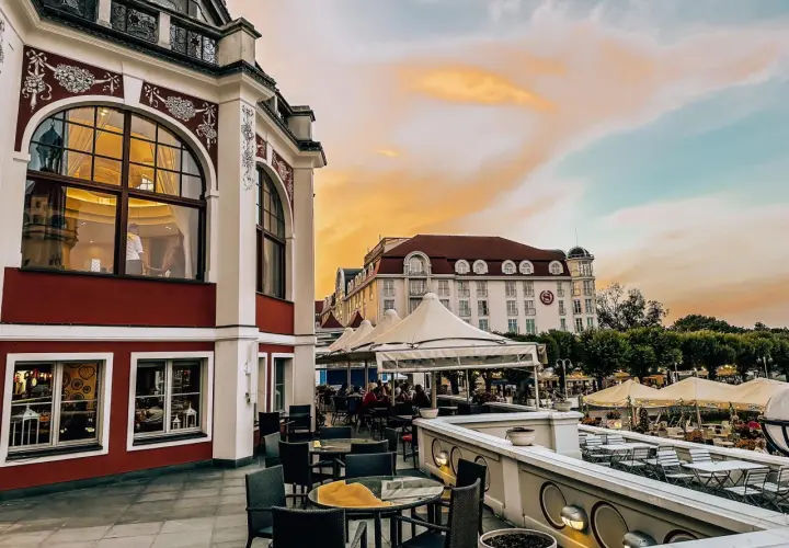 Eleganckie tarasy z widokiem na morze, idealne na kolację w jednej z nowych restauracji w Gdańsku. Zachód słońca maluje niebo na pomarańczowo.