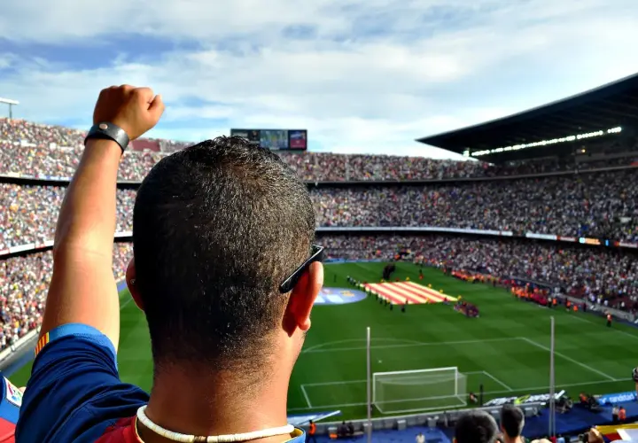 Kibic z podniesioną pięścią na stadionie, dumny jak właściciel Barcelony.
