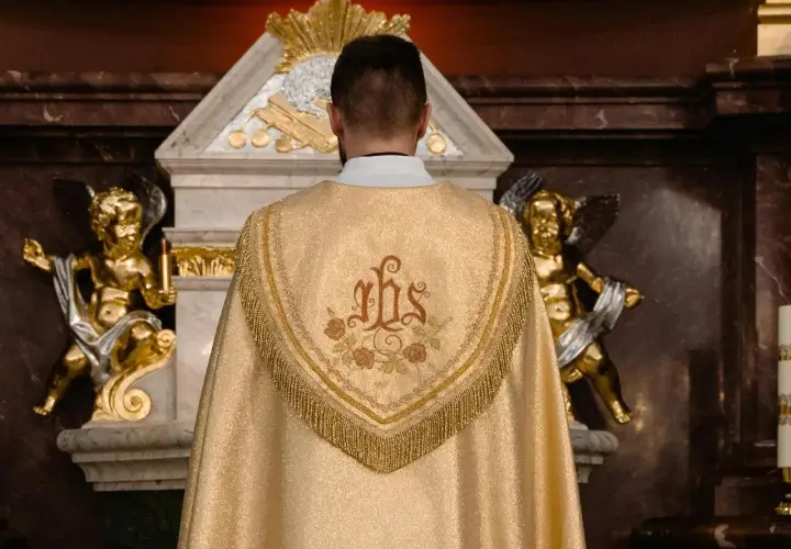 Kapłan w złotej kapie z symbolem IHS. Złote aniołki po bokach ołtarza. Zastanawiasz się, ile trwa msza święta?