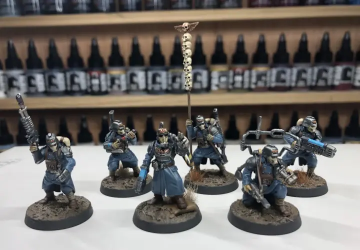 Krieg command squad w niebieskich mundurach, z karabinami i sztandar z czaszkami, gotowi do walki.