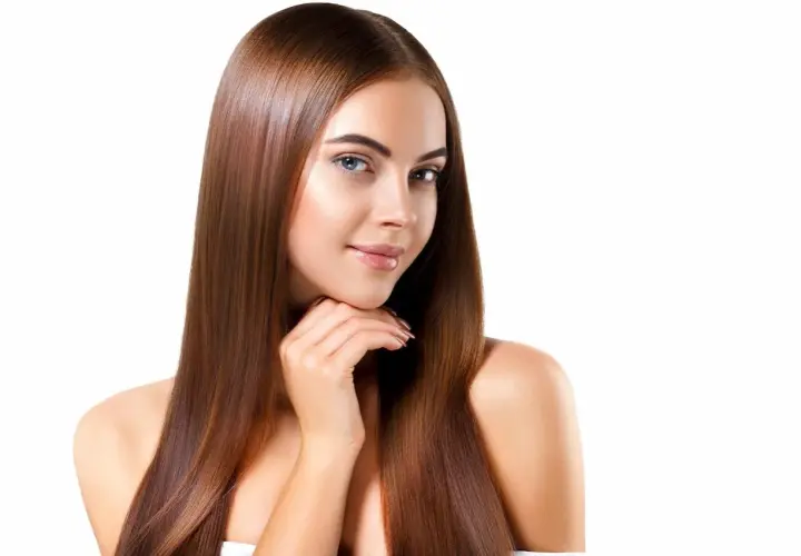 Mujer con cabello largo y liso, color de pelo avellana con reflejos dorados, sonríe suavemente.