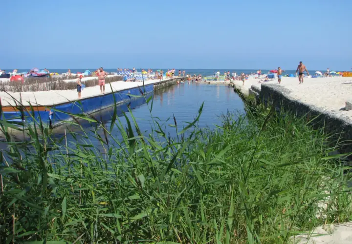 Słoneczny dzień na plaży w Karwi. Ludzie odpoczywają nad wodą, a w oddali widać morze. Karwia promenada tętni życiem.