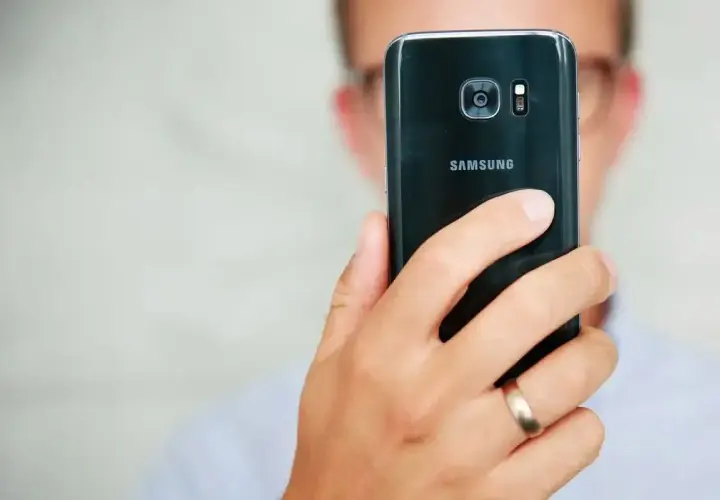 Osoba trzyma czarny telefon Samsung, pokazując tył z aparatem. Dowiedz się, jak poprawić jakość aparatu w telefonie Samsung.