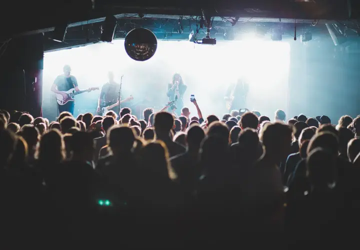 Publik njuter av en konsert i Stockholm idag. Bandet spelar på scenen medan publiken filmar med sina mobiler.