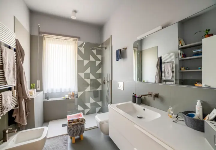Bagno moderno con doccia su finestra, lavabo, bidet e scalda-asciugamani.