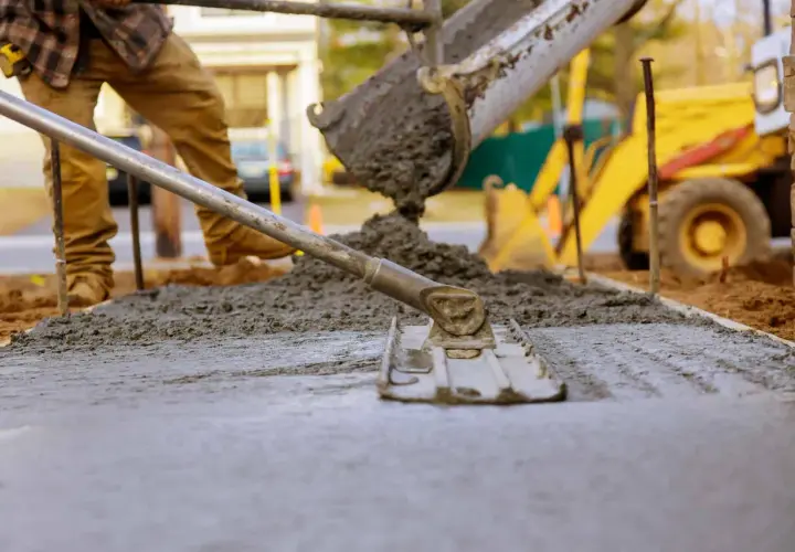 Betonowanie trwa, mimo że temperatura może być wyzwaniem. Robotnik wyrównuje świeży beton, który właśnie wylano z betoniarki.
