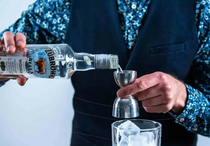 Wybierasz jaka wódka na wesele? Żubrówka Biała idealna do drinków, nalewana przez barmana do kieliszka z lodem.