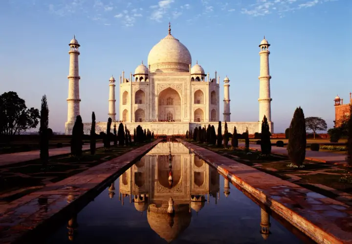 Der Taj Mahal, eine Moschee und ein Mausoleum, spiegelt sich im Wasser.