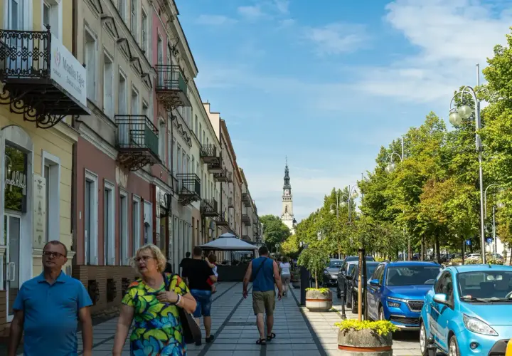 Spacerem ulicą w Częstochowie, w oddali widać wieżę Jasnej Góry. Trasa pielgrzymkowa tętni życiem.