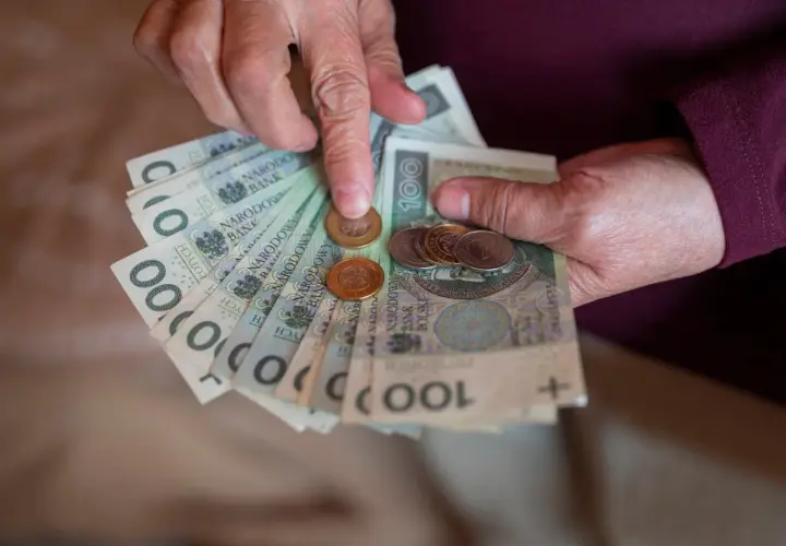 Dłonie liczą banknoty i monety. Warto sprawdzić 13 emerytura tabela 2026, by poznać przyszłe świadczenia.