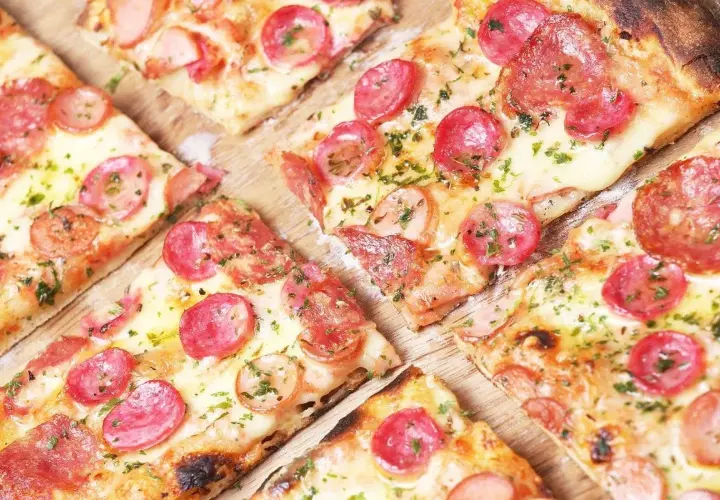 Kawałki pysznej, gorącej pizza włoska z kiełbasą i serem, posypane ziołami. Idealna na spotkanie z przyjaciółmi.