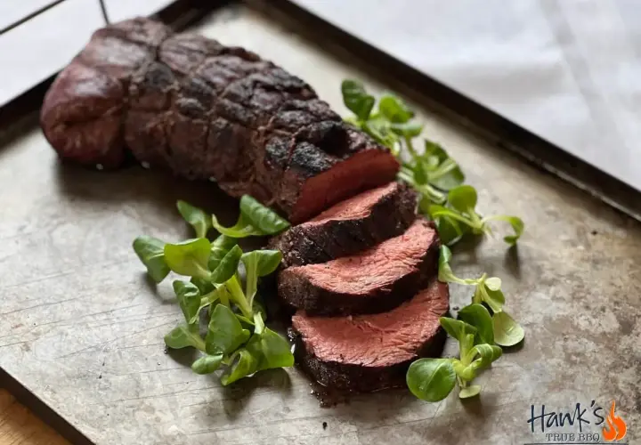 Perfekt grillad oxfilé, saftig och röd i mitten, serverad med färska gröna blad på en rustik plåt. En riktig höjdare för grillmästaren!
