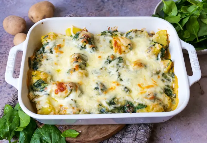 Ein köstlicher Kartoffel-Spinat-Auflauf mit geschmolzenem Käse, bereit zum Servieren. Frische Kartoffeln und Spinat sind die Basis dieses herzhaften Gerichts.