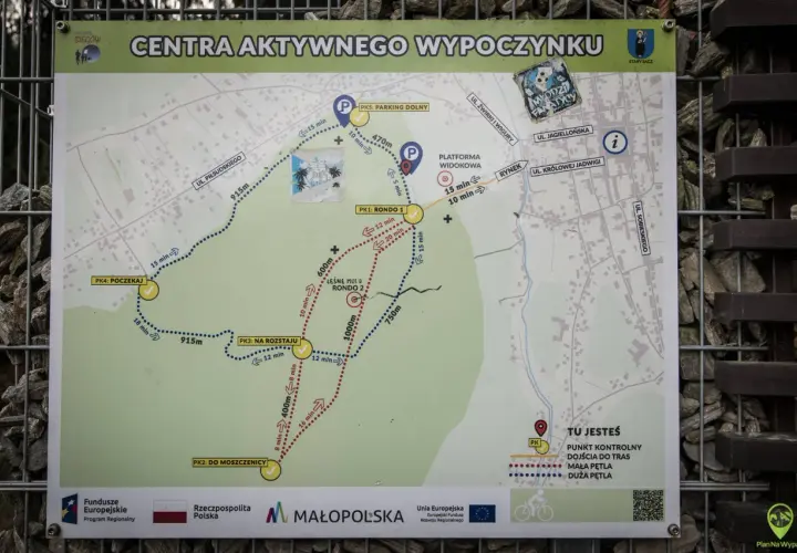 Mapa szlaku turystycznego z zaznaczonymi punktami kontrolnymi, trasami i odległościami. Widać fragment leśnego molo.