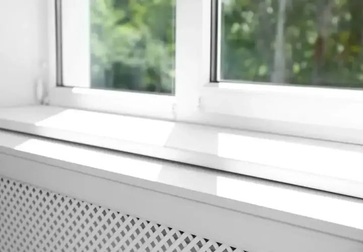 Biały parapet zewnętrzny z widocznym uszczelnieniem, chroniący przed warunkami atmosferycznymi.