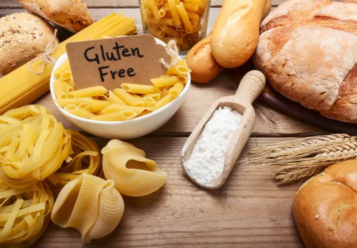 Różne rodzaje makaronów i pieczywa, a także mąka i kłosy zbóż. Etykieta "Gluten Free" sugeruje dyskusję: czy gluten jest zdrowy?
