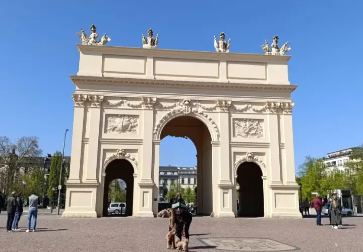 Brama Brandenburska w Poczdamie, gdzie leży to piękne miasto, z ludźmi i psami na placu.