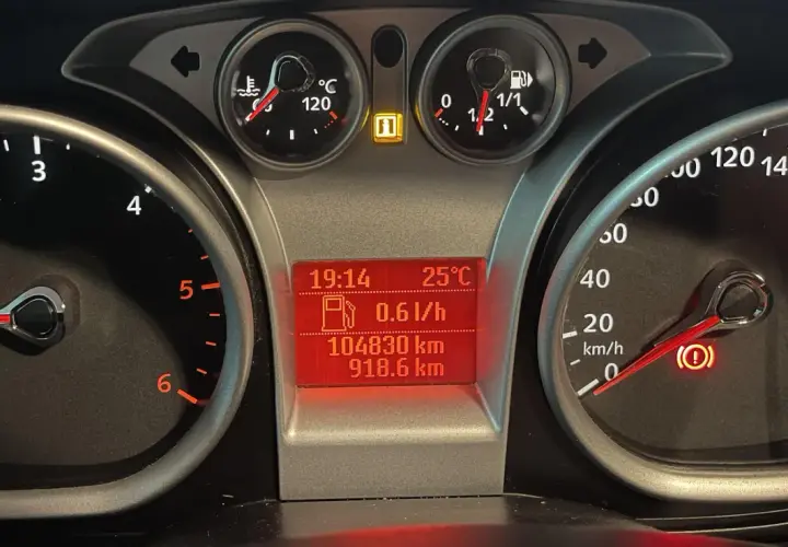 Deska rozdzielcza Ford Focus z kontrolkami: temperatura, paliwo, przebieg, prędkościomierz i kontrolka hamulca ręcznego.