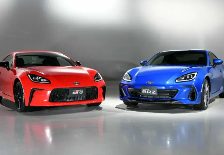 Dwa sportowe coupe, czerwona Toyota GR86 i niebieski Subaru BRZ, stoją obok siebie, gotowe do wyścigu.