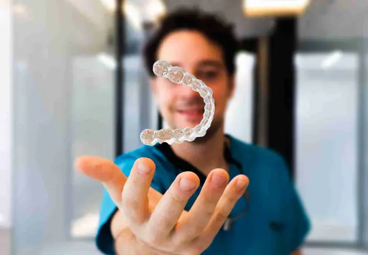 Un dentista sonriente muestra un alineador invisible, explicando cómo funcionan los alineadores invisibles para corregir la sonrisa.