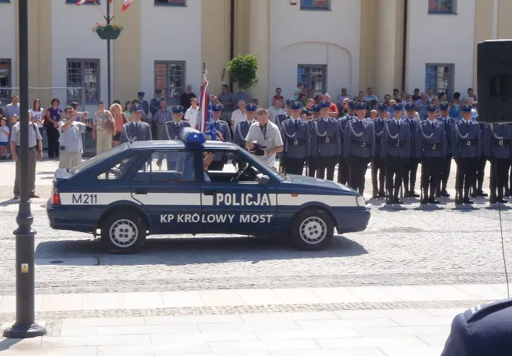 U pana Boga w ogródku obsada: policjanci w mundurach stoją w szeregu obok radiowozu.