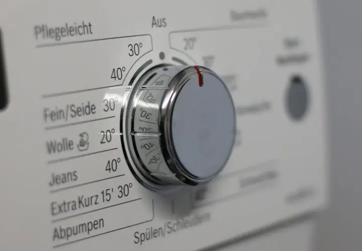 Drehknopf einer Waschmaschine mit verschiedenen Waschprogrammen wie Pflegeleicht, Fein/Seide, Wolle und Jeans.