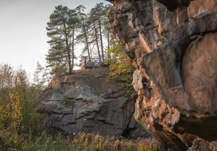 Kamienne miasto z platformą widokową wśród sosen. Skały tworzą naturalne miasto, a drewniana konstrukcja zaprasza do podziwiania krajobrazu.