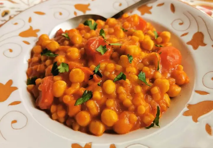 Piatto di ceci e pomodoro, guarnito con prezzemolo. Un sapore che ricorda la peretta formaggio, un classico.