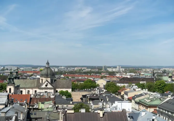 Widok na krakowskie dachy i kościół z kopułą. W tle nowoczesne budynki, które mogą wpływać na ceny mieszkań Kraków.