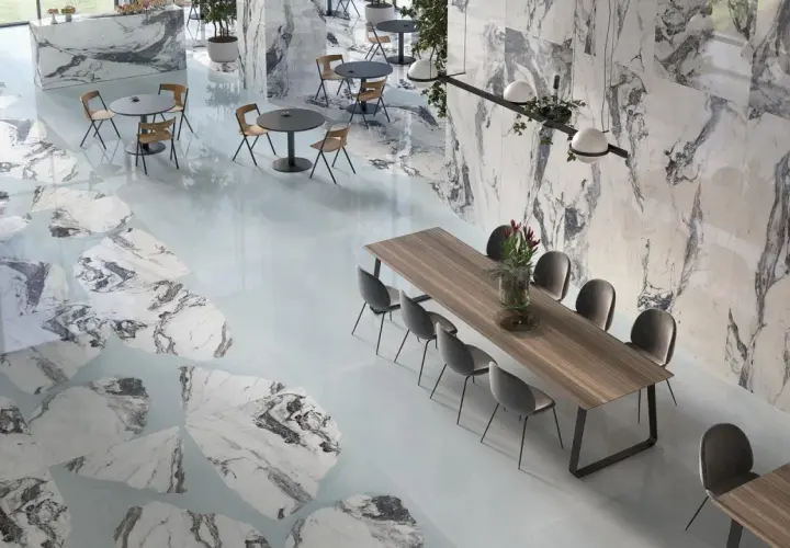 Interni eleganti con pavimenti e pareti che richiamano i **marmo di Carrara colori** con venature grigie e bianche, tavoli e sedie moderne.