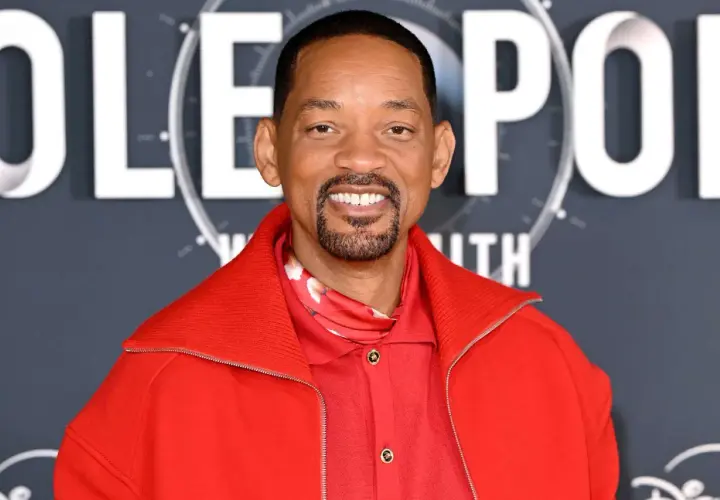 Will Smith, souriant, porte une veste rouge vif. On peut lire "POLE" en lettres blanches derrière lui, suggérant son prochain film.