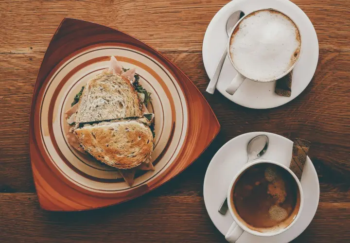 Ein Sandwich und ein Café Americano auf einem Holztisch.