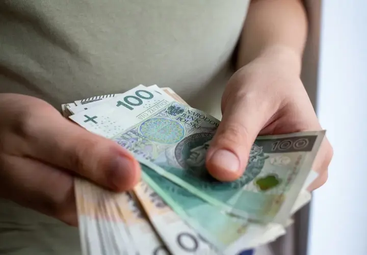 Dłonie liczą banknoty 100 zł. To może być pomoc de minimis dla przedsiębiorcy.