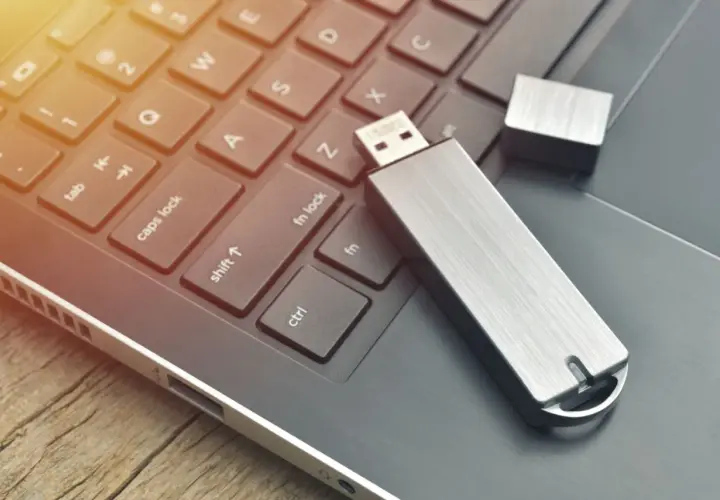 Silberner USB-Stick liegt auf einer Laptop-Tastatur. Vielleicht hilft das, den USB-Stick RAW zu reparieren.