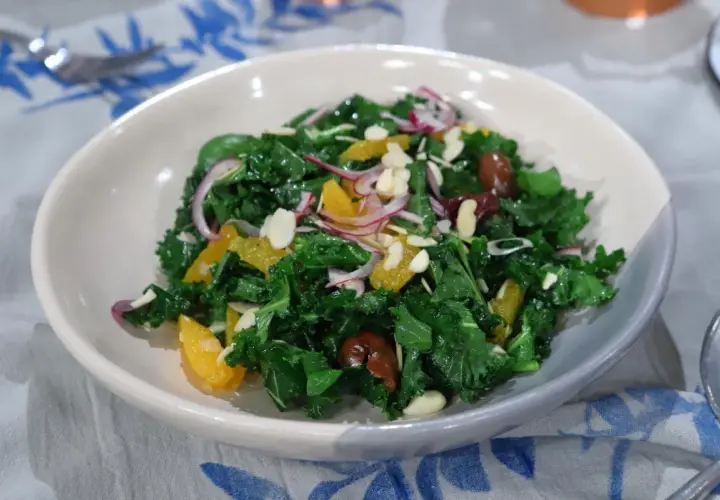 Ensalada siciliana vibrante con col rizada, gajos de naranja, cebolla morada, aceitunas y almendras laminadas.
