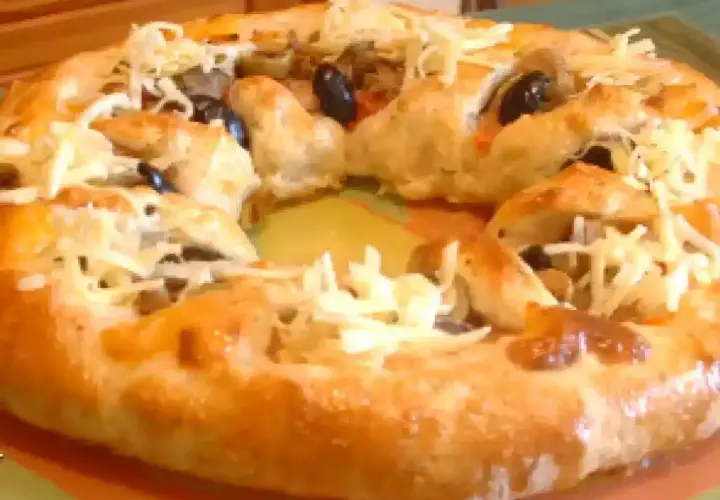 Pizza maison avec une croûte dorée, garnie d'olives noires et de fromage râpé. Parfait pour une recette pâte à pizza rapide.