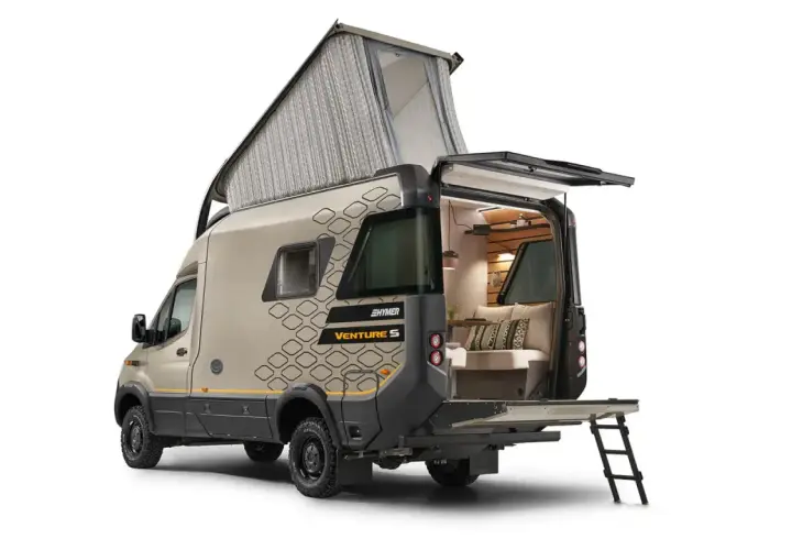 Hymer Venture S z podniesionym dachem i otwartym tyłem, ukazujący przytulne wnętrze z kanapą i poduszkami.