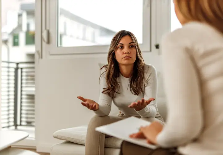 Kobieta rozmawia z psychologiem, gestykulując rękami.