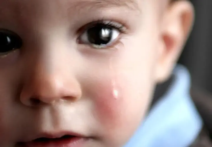 Un bambino piange, una lacrima scende sulla sua guancia arrossata. L'orzaiolo sui suoi occhietti lo fa soffrire.