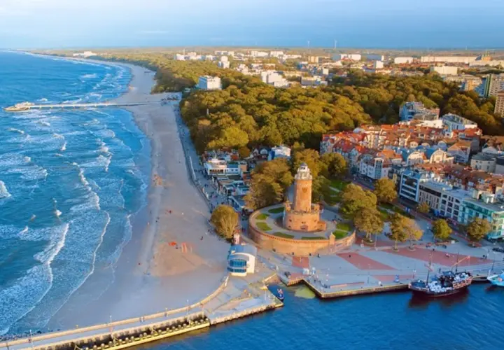 Malownicza miejscowość nad morzem z latarnią morską, plażą i molo.