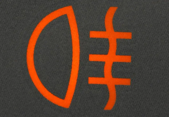 Pomarańczowy symbol świateł dziennych na ciemnym tle.