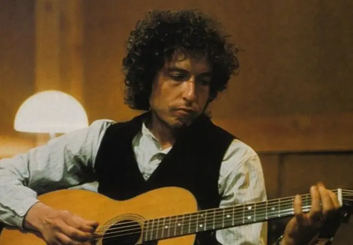 Bob Dylan gra na gitarze, tworząc ponadczasowe utwory.