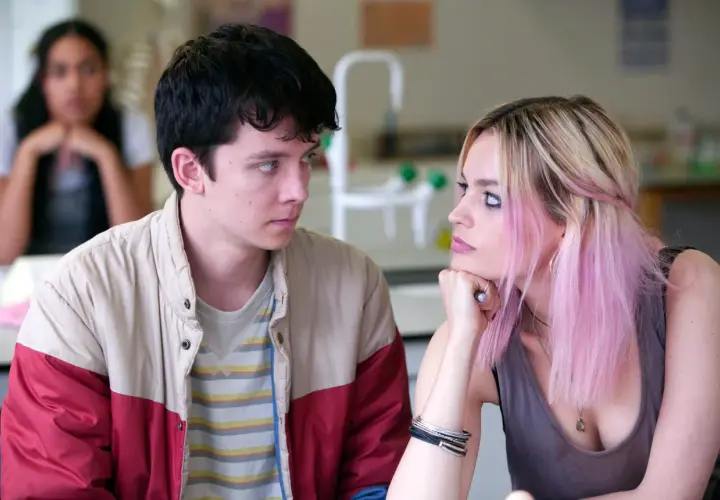Una recensione di Sex Education: Otis e Maeve si guardano intensamente, mentre un'altra ragazza è sfocata sullo sfondo.