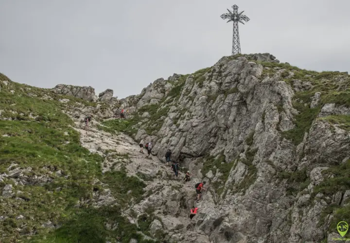 Grupa turystów wspina się po kamienistym zboczu Giewontu. Czy wejście na Giewont jest trudne? Trasa wymaga kondycji i ostrożności.