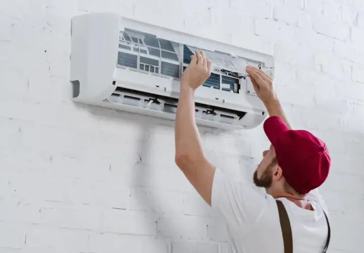 Técnico instalando un aire acondicionado inverter, ajustando filtros.